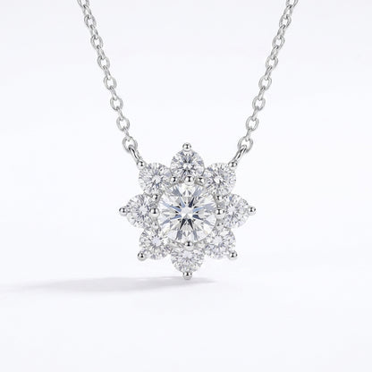 A silver-tone necklace with a snowflake-shaped cluster pendant featuring a central round diamond surrounded by smaller diamonds, shown on a clean white background.